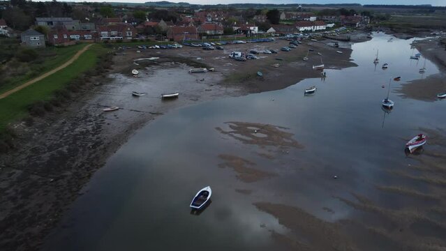 Aerial Drone Shot Flying Over Creek at Low Tide with Sailing Boats and Boathouse in Burnham Overy Staithe North Norfolk on Cloudy Gloomy Moody Day UK
