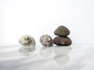 Fototapeta na wymiar Zen basalt stone and seashells on white marble background