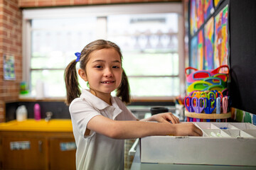 Young schoolgirl in classroom smiling at camera