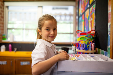 Young Caucasian schoolgirl in classroom smiling at camera
