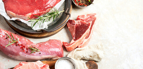 Assortment of raw meats on grey background.