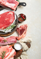 Assortment of raw meats on grey background.