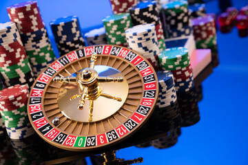 Casino theme.  Gambling games. Roulette wheel and poker chips on blue background.