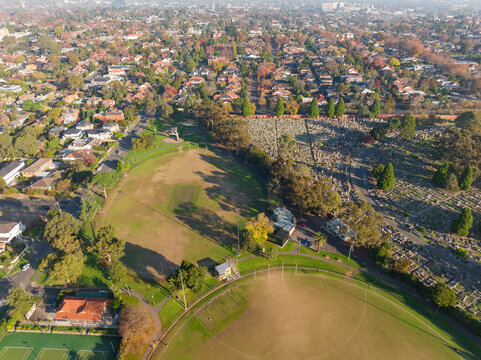 Aerial view of sporting ovals alongside a suburban cemetery