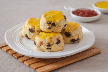 Raisin scones on white plate and jam.