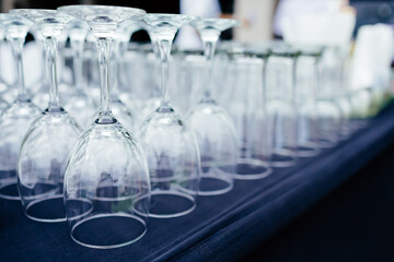 Several wine glasses upside down lined up on the table with other glasses. Reflecting light, shining, beautiful, in the party