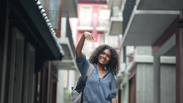 african business woman having lifr style at outdoor pedestrian space. woman in relaxing holding laptop. girl walking in relaxing and happy. she call and hand up to someone or friend.