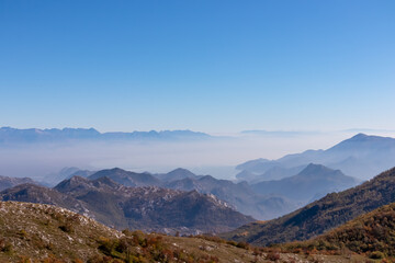 Panoramic view of dramatic karst mountain chains Dinaric Alps surrounding the Lake Skadar National Park seen from Goli Vrh, Montenegro, Balkan, Europe. Valley is covered by mystical fog, blue hills