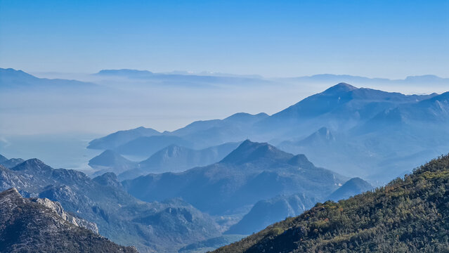 Panoramic view of dramatic karst mountain chains Dinaric Alps surrounding the Lake Skadar National Park seen from Goli Vrh, Montenegro, Balkan, Europe. Valley is covered by mystical fog, blue hills