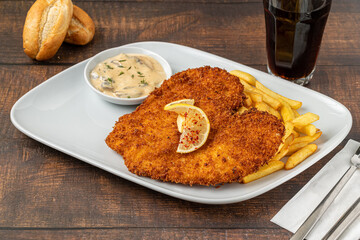 Chicken schnitzel with butter and potato salad on white porcelain plate