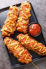 Korean corndogs Korean street food it consists of mozzarella cheese and hotdog skewered then battered and fried to golden brown perfection closeup on the plate. Vertical top view from above