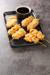Popular Osaka street food Kushikatsu Kushiage are skewered meat and veggies that are breaded with panko and deep fried closeup on the plate on the table. Vertical