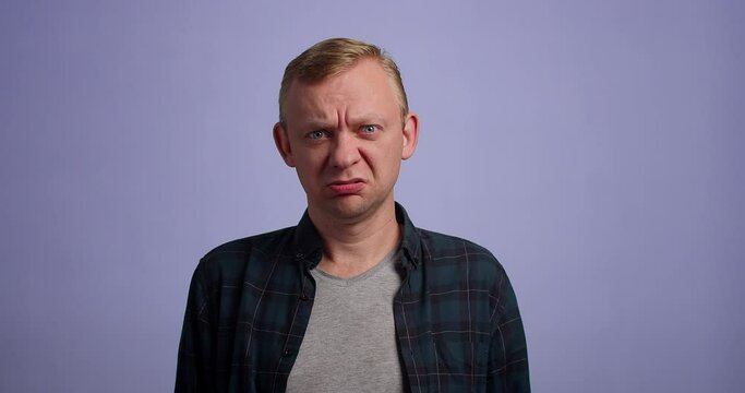 Man looking annoyed and asking wtf while posing against blue background. studio shot