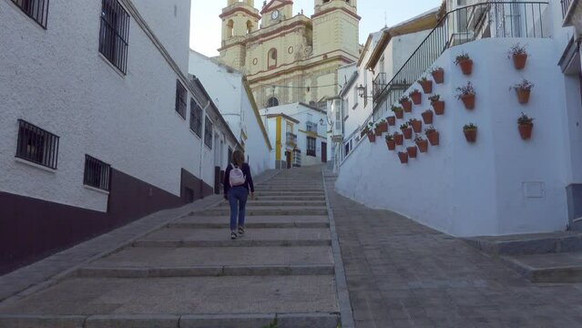 Tourist woman strolling through the steep streets with steps leading to the cathedral located at the top of the village, Olvera, Cadiz.