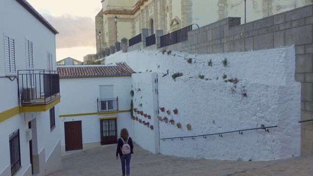 Tourist woman strolling through the steep streets with steps leading to the cathedral located at the top of the village, Olvera, Cadiz.