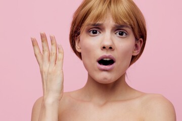 a close horizontal beauty photo on a pink background of a surprised woman with her hair pinned up...