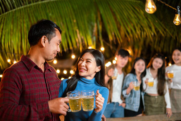 Happy young Asian couple having a party with friends while drinking beer.