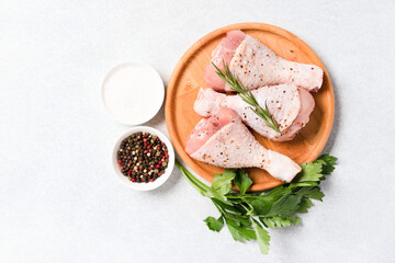 Cooking chicken drumsticks with seasonings and spices on wooden plate over white table background. Raw chicken legs ready to cook. Organic meat, healthy eating