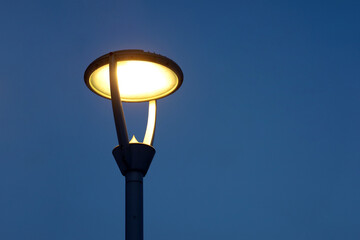 Glowing led lamp on evening sky background. Electric lighting, energy-saving street lantern