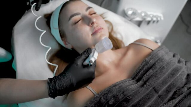 The specialist cleans the face of a lady with the help of the oxygen procedure,Top view
