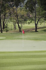 golf course with red flag on putting green 