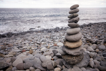 Tall balanced pile of pebble stones on a stony beach in Madeira, Portugal.