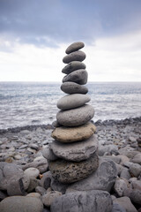 Fototapeta na wymiar Tall balanced stack of pebble stones on a stony beach in Madeira, Portugal.