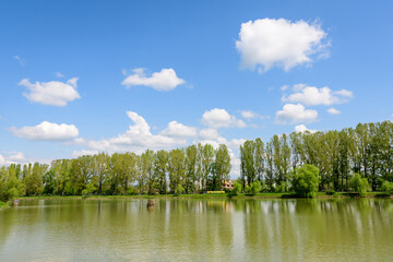 Small lake with a woodmill and an island from Chindiei Park (Parcul Chindiei) in Targoviste, Romania, in a sunny spring day with white clouds and blue sky