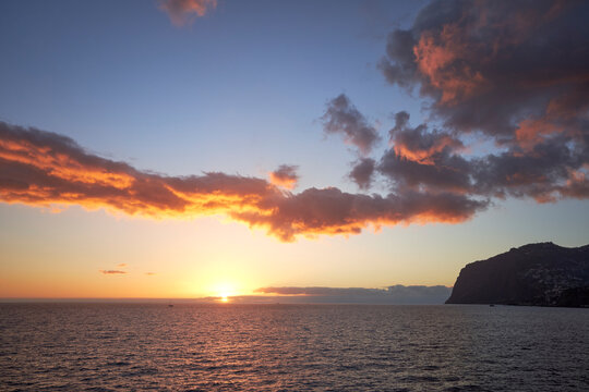 Beautiful sunset in Madeira, sun, clouds and sea. Summer holiday wallpaper.