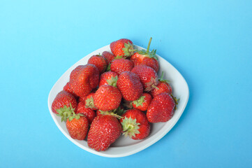 Strawberries on a plate on a blue background