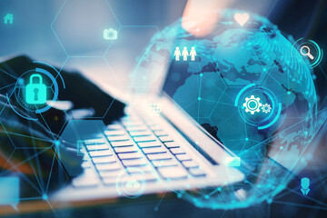 Close up of backlit female hands using laptop with glowing globe and business icons hologram on blurry background. Global network and data exchange concept. Double exposure.