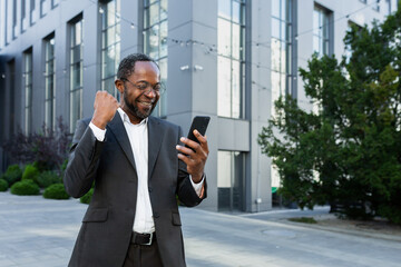 African american businessman boss outside modern office building using phone, senior man...