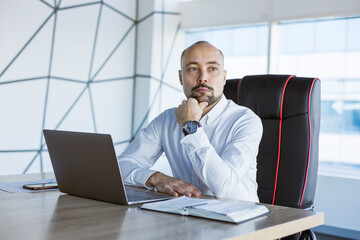 Portrait of a business young successful man in a modern office sitting at a table