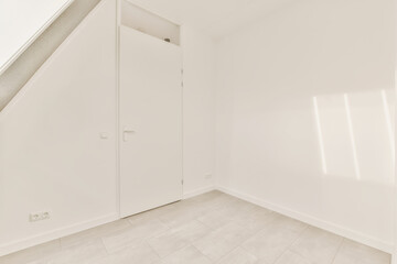 an empty room with white walls and flooring, there is a door in the corner that leads to another...