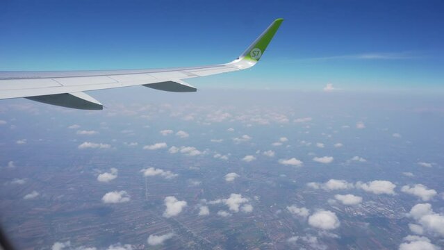 Spring, 2018 - Thailand - The wing of a C7 airline plane flies above the clouds during the day.
