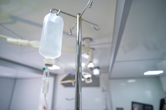 Intravenous or Iv fluids drip bottle hanging on a metal pole in hospital emergency room. Equipment and medical devices.