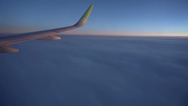 Spring, 2018 - Thailand - The wing of a S7 airline plane flies above the clouds at sunset time.