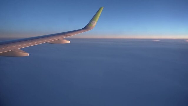 Spring, 2018 - Thailand - The wing of a S7 airline plane flies above the clouds at sunset time.