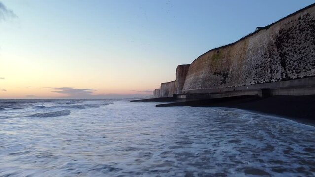 Beautiful sunset on Brighton coast with sea waves and beach in England