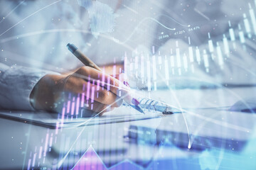 Double exposure of woman's hands making notes with forex graph hologram. Concept stock market analysis.