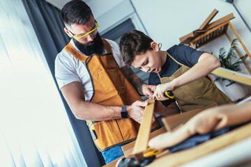 Father and son making furniture of wooden plank at home