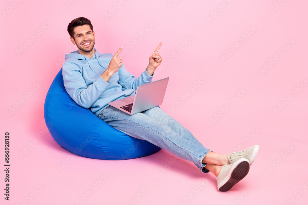 Poster photo of glad nice man sit comfy bag presenting empty space recommend novelty quality device empty s