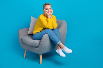 Full length photo of satisfied dreamy cute blonde short hair woman touch cheeks comfort armchair lovely look you isolated on blue color background