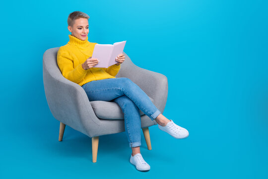 Full body length photo of concentrated reader lady short blonde hairdo wear yellow knitted pullover read new book isolated on blue color background