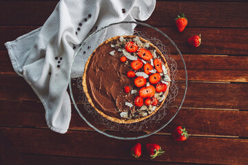 Chocolate tart decorated with strawberries and coconut flakes
