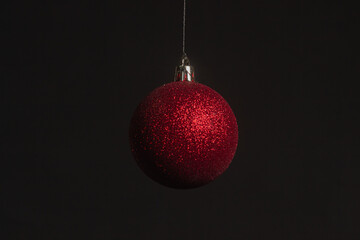 Red Christmas ball on a Christmas tree with a garland on the black background