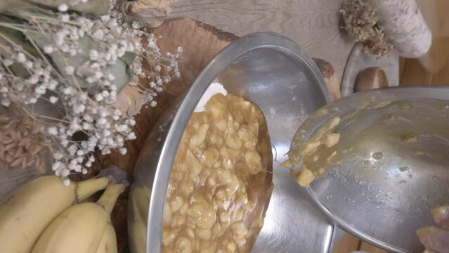 Apple filling is poured into a bowl full of flour and mixed around.