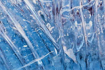 Bubbles and cracks inside natural ice. A fragment of a festive ice figure before Christmas and New Year. Optical phenomena. Abstract background. Close up. Selective focus.