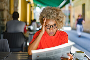 Attractive woman reading a newspaper at outdoor cafe