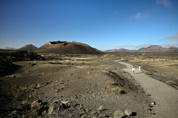 Menschen Wandern auf der Kanareninsel Lanzarote bei blauem Himmel zum Vulkan Es Cuervo 